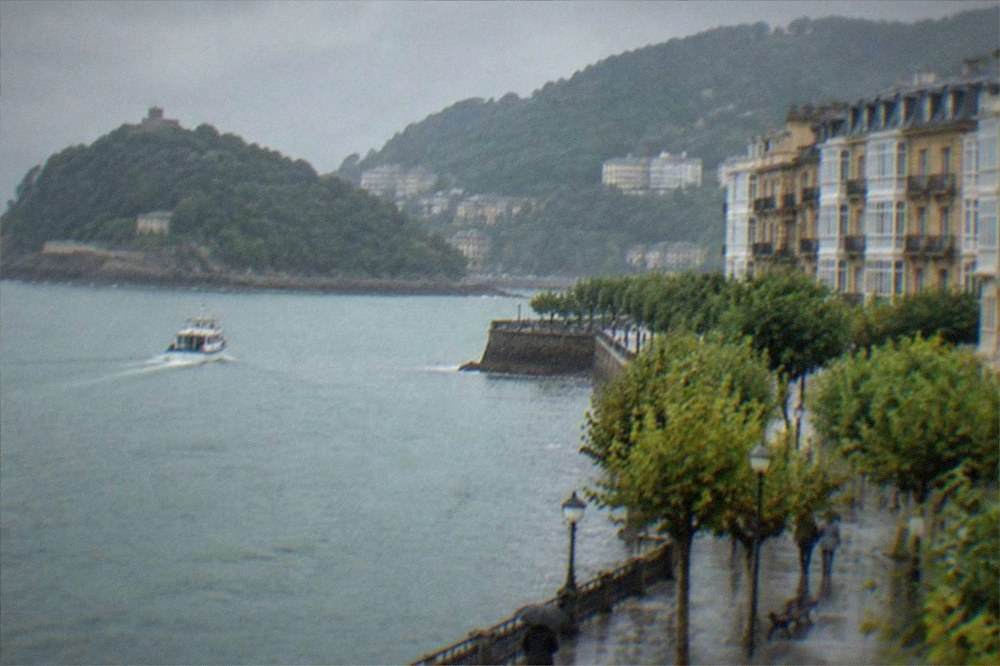 A small boat crossing a grey bay toward a wooded island