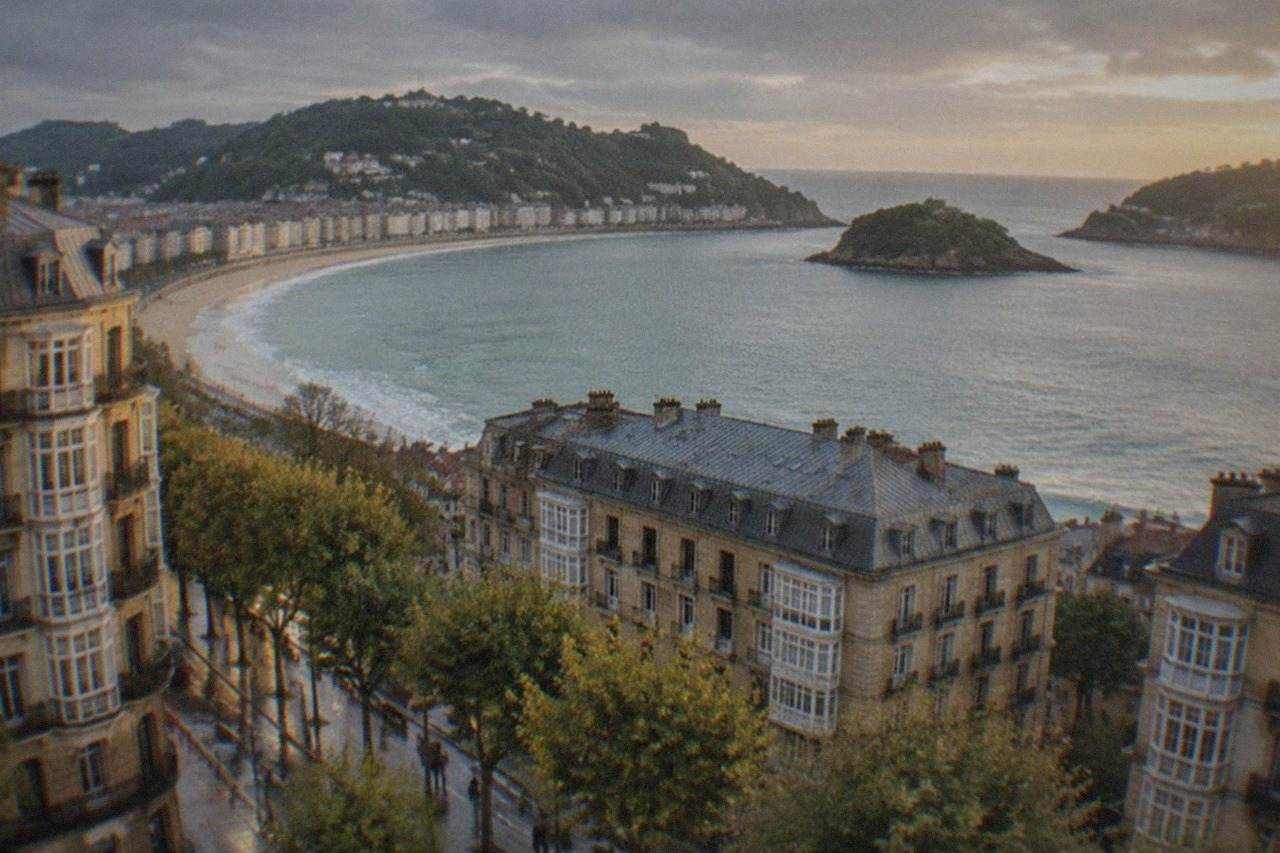 The curved bay of San Sebastián seen from above, with Santa Clara island offshore and green hills on either side
