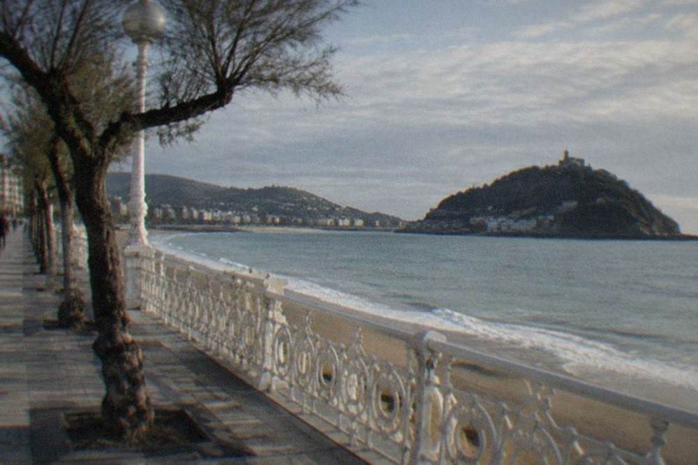 White railings along the La Concha promenade with the island and hills in the background