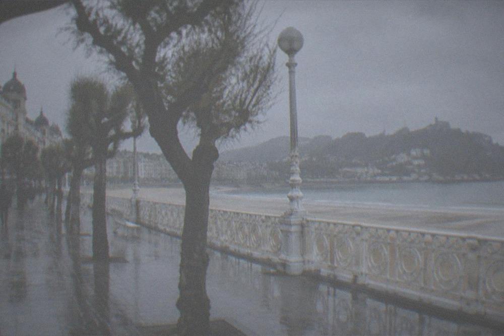 Rain clouds over the bay with wet sand and a partly covered promenade