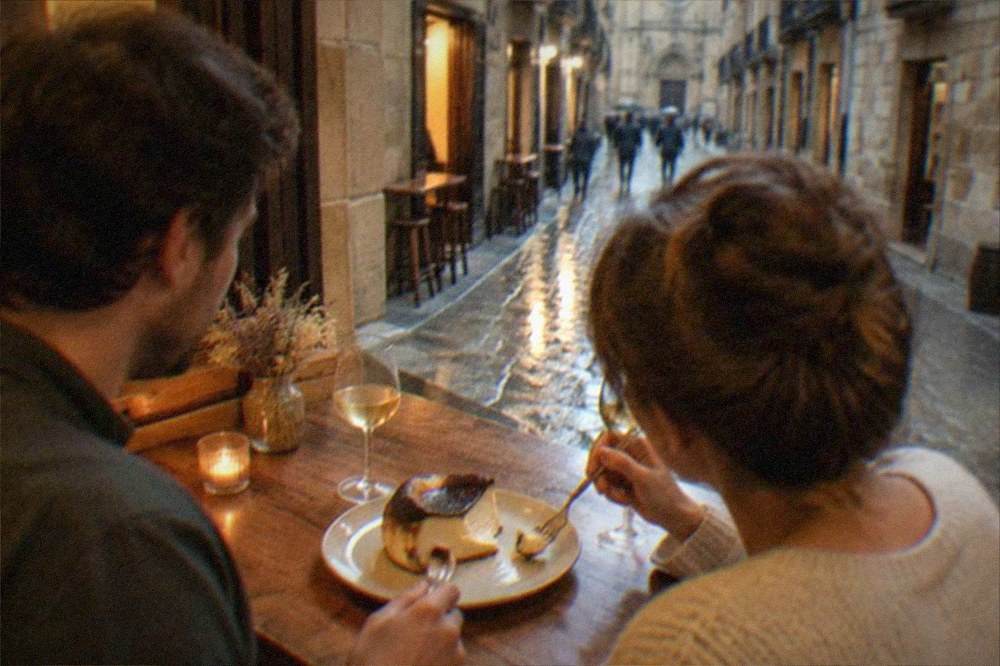 A couple sharing a basque burnt cheesecake slice at a wooden table in a warm tavern