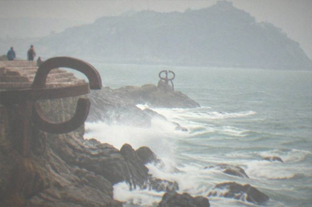 Steel sculptures of the Peine del Viento standing on rocks at the water's edge
