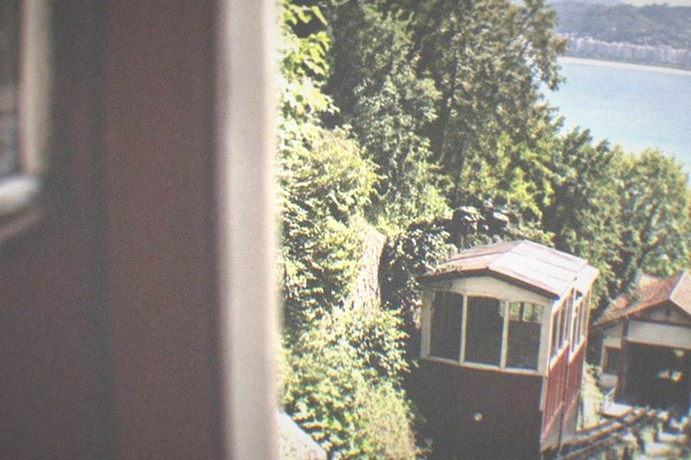 A wooden funicular car climbing the wooded slope of Monte Igueldo