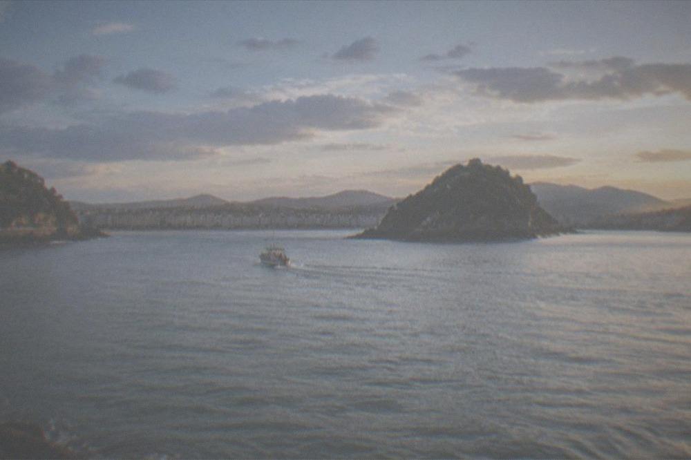 A small boat crossing La Concha bay toward Santa Clara island on a clear day