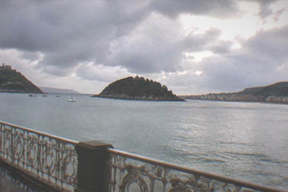 Rain clouds over La Concha bay seen from a covered promenade railing