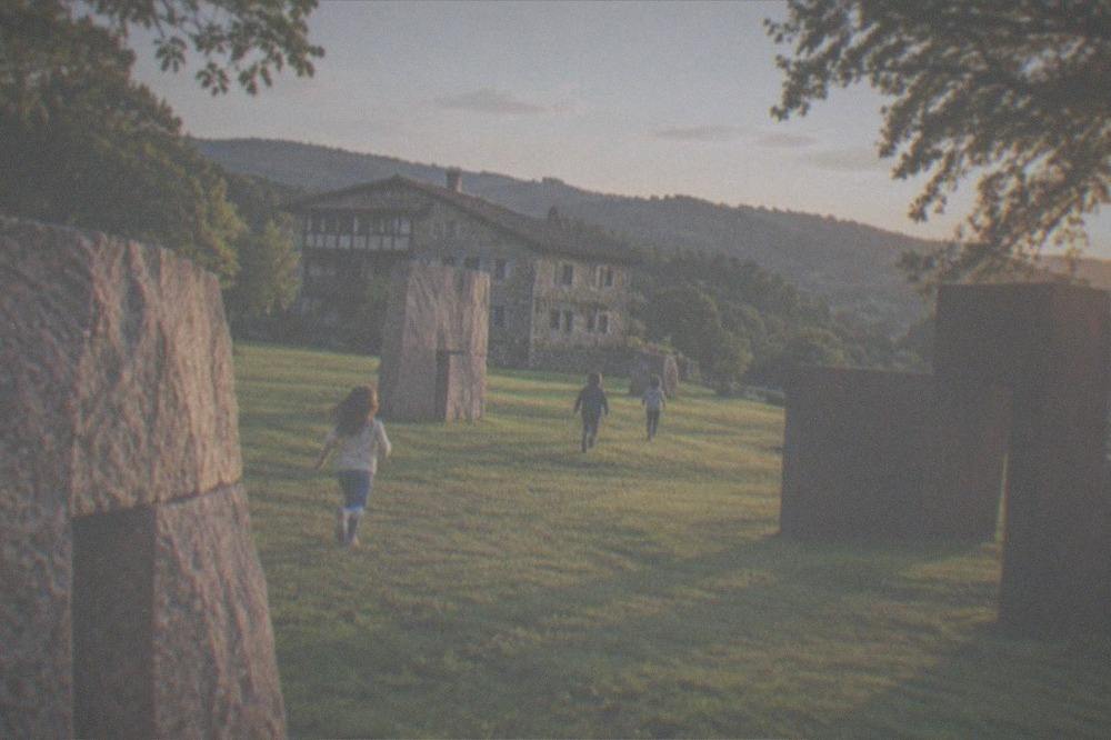 Children running between large stone sculptures in the garden at Chillida Leku