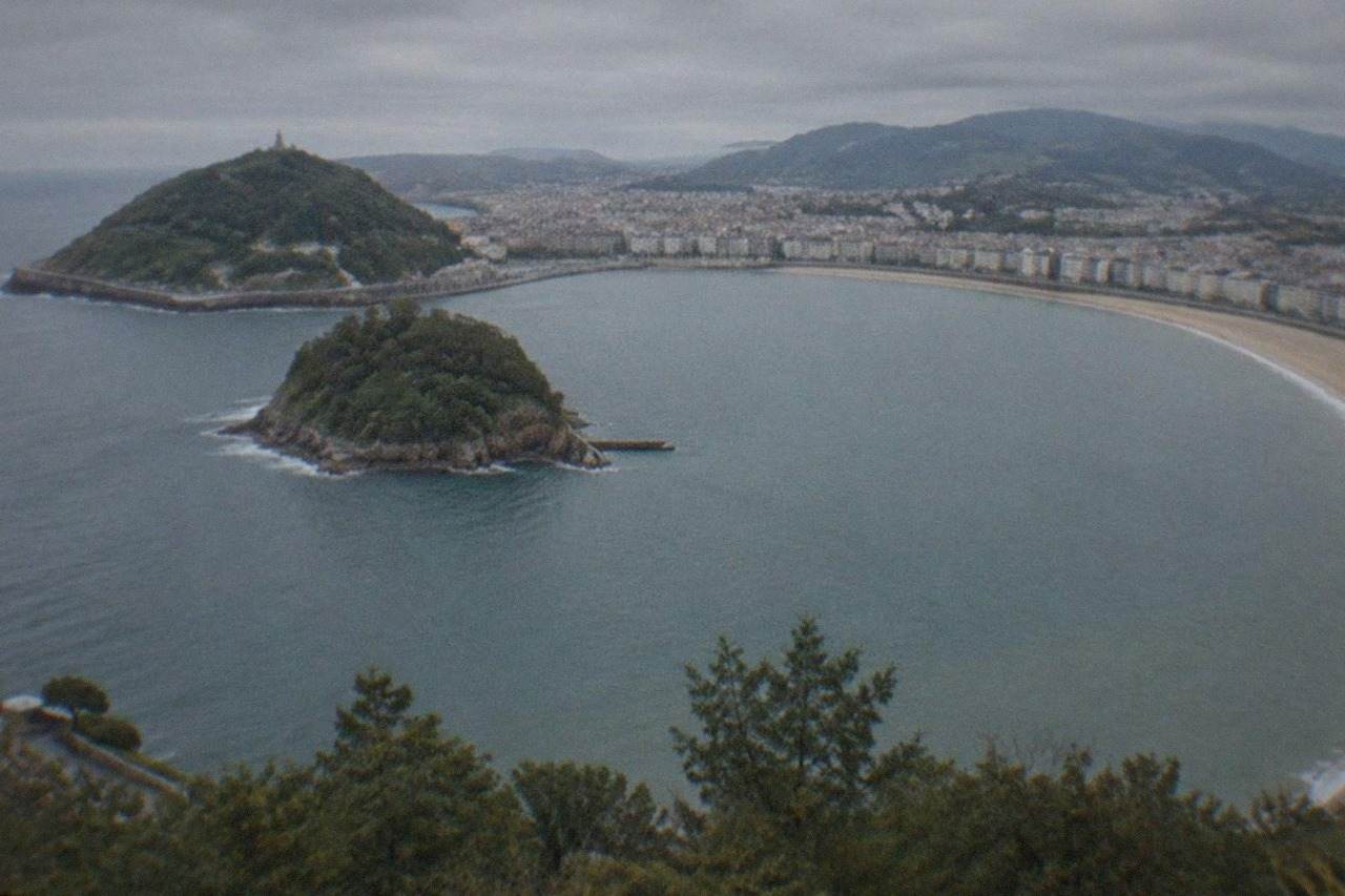 La Concha bay in San Sebastián seen from above, with the beach curving round the water and Santa Clara island in the middle
