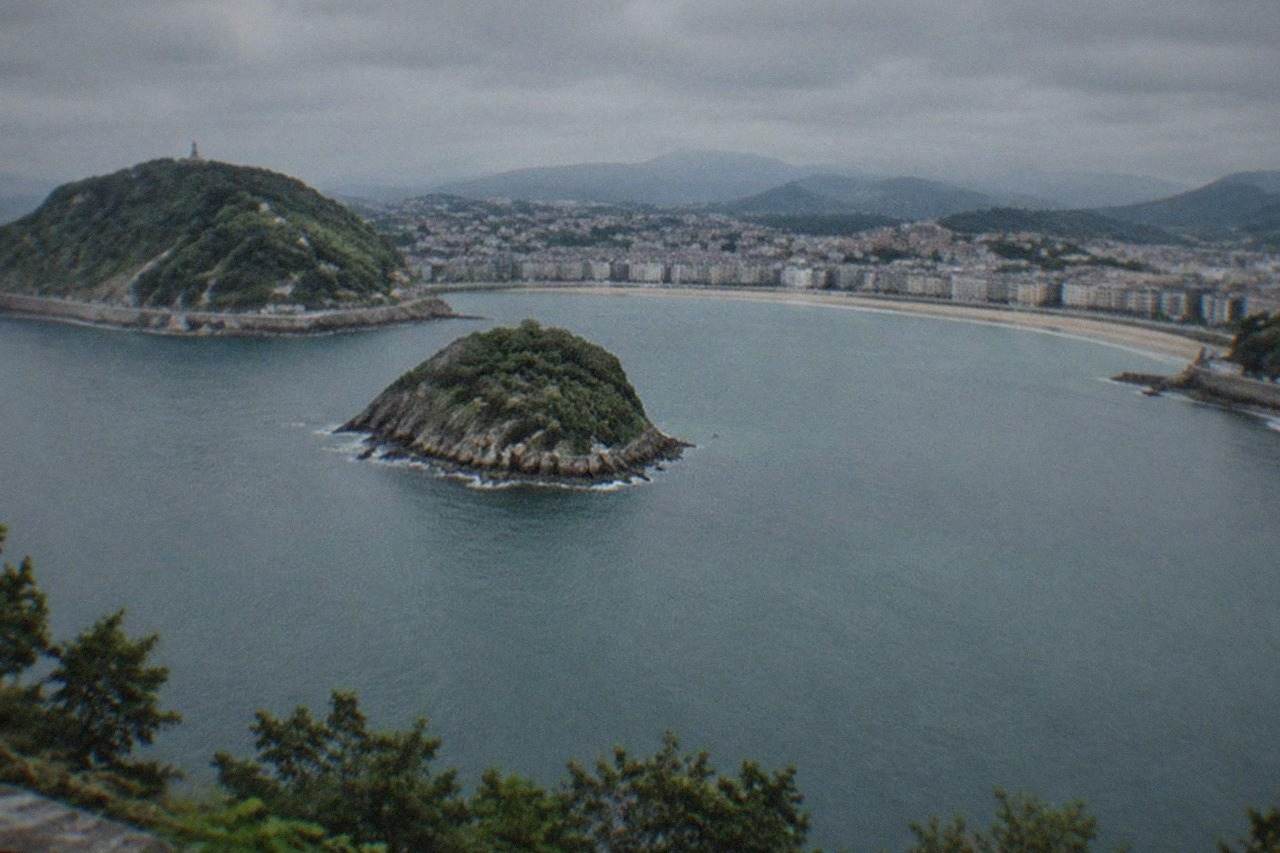 La Concha bay in San Sebastián seen from above, with the beach curving between two wooded hills