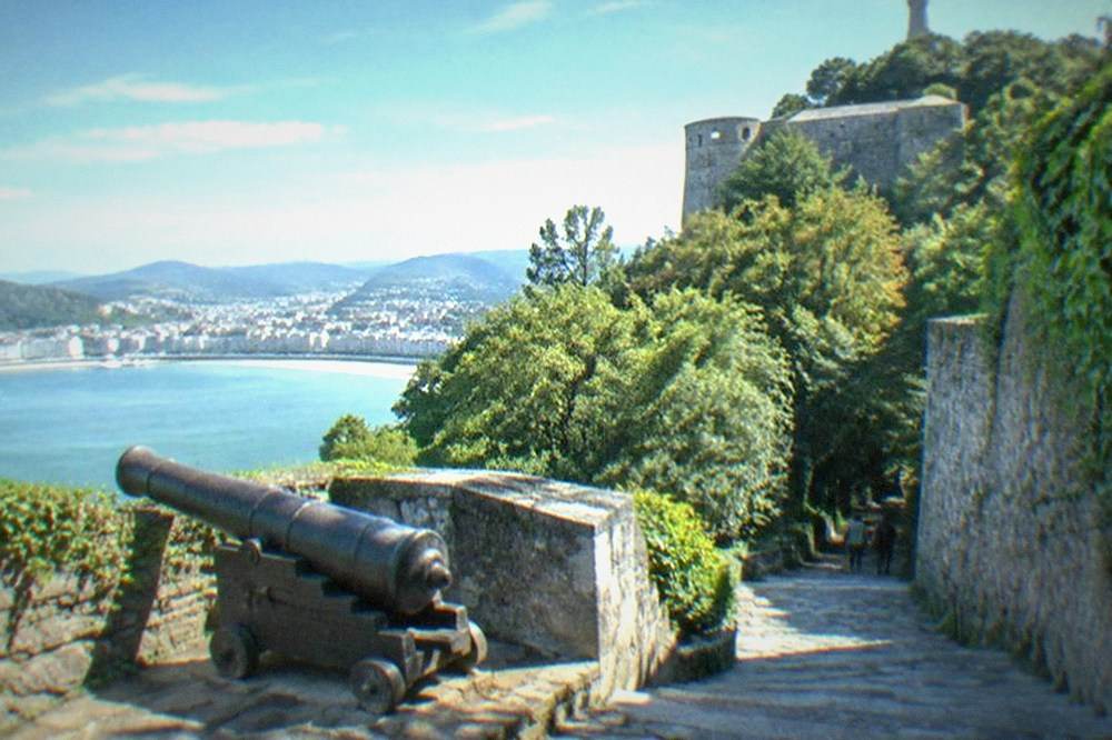 A stone fortress and a large sculpture on the wooded summit of Monte Urgull above San Sebastián