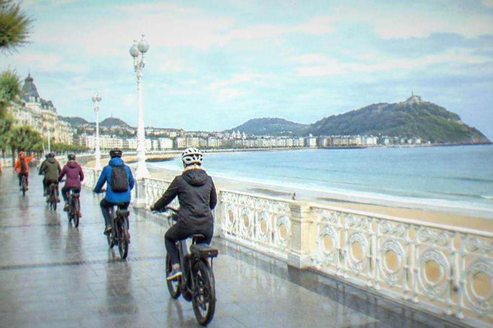 A guide leading a small group of e-bike riders along the La Concha promenade