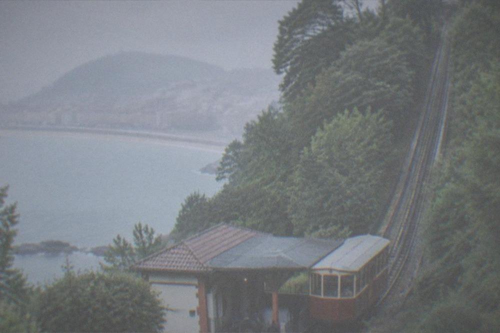 The wooden funicular car at the base of Monte Igueldo with riders nearby