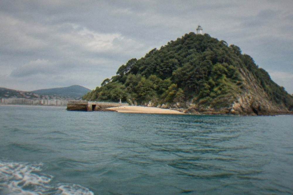 Santa Clara island seen from a boat, with the lighthouse above a narrow strip of sand