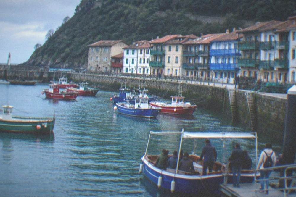 Passengers in light jackets boarding a small boat at a harbour pontoon in the morning