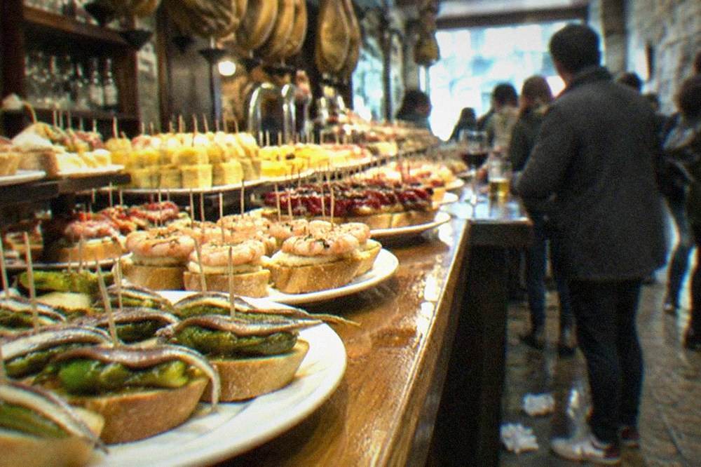 A plate of finished pintxos on a bar counter with skewers and small bread slices