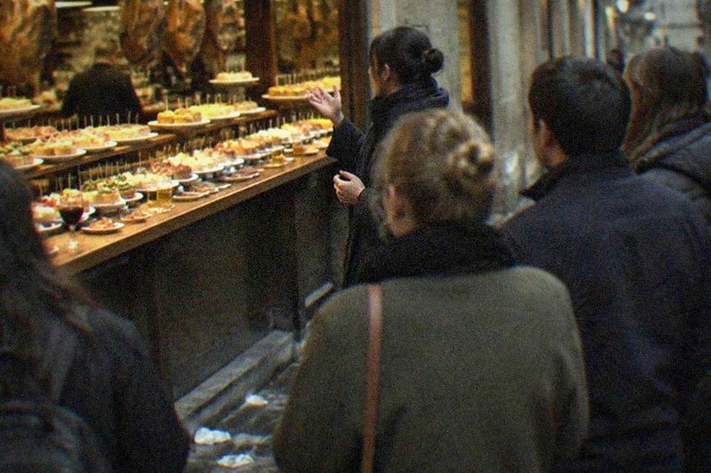 A guide talking to a small group outside a pintxo bar at night