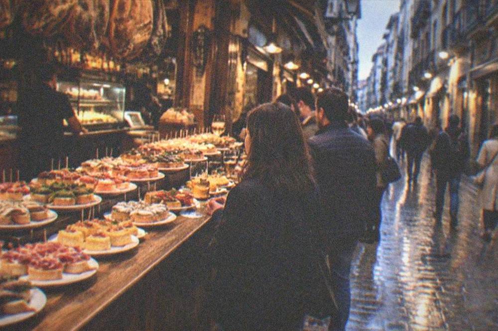 An Old Town street at dusk with bar lights and people walking between pintxo bars