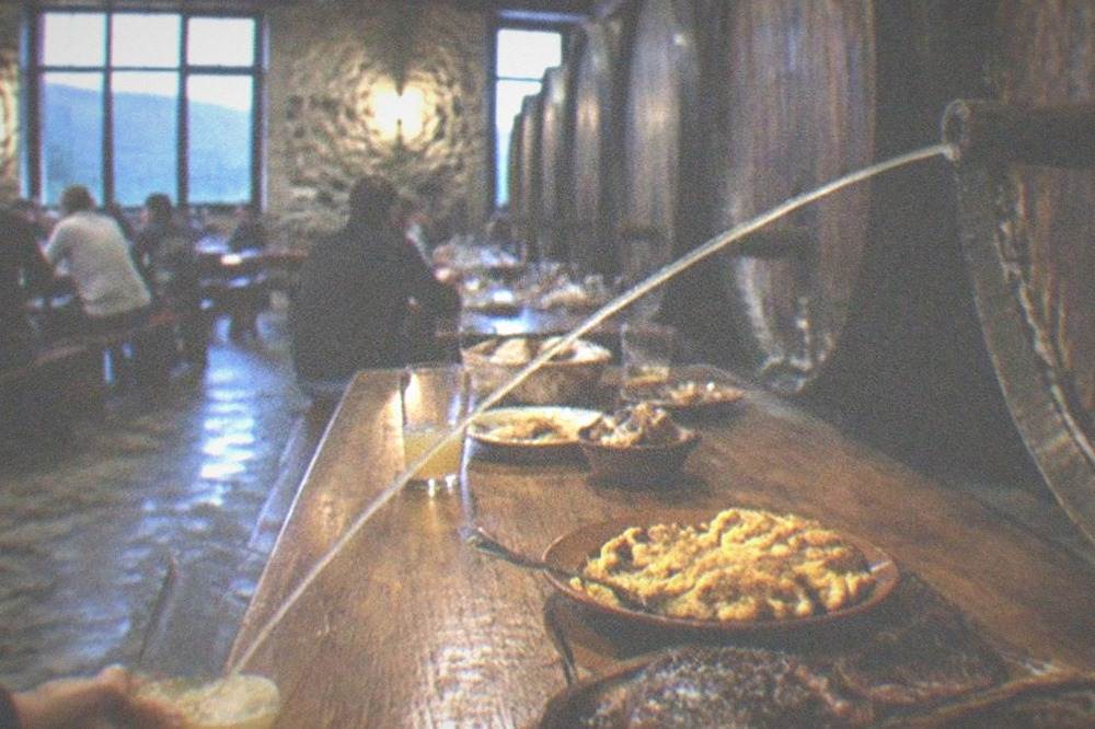 Cider barrels in a Basque cider house with cider pouring from the barrel