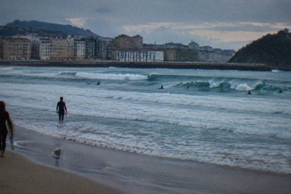 Waves breaking at Zurriola beach with the Gros district buildings behind