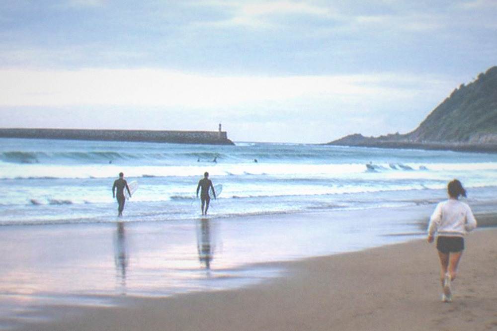 Zurriola beach on a summer morning with clean waves and a mostly empty sand