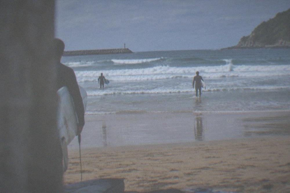 A folded wetsuit and a towel laid out beside a surfboard bag