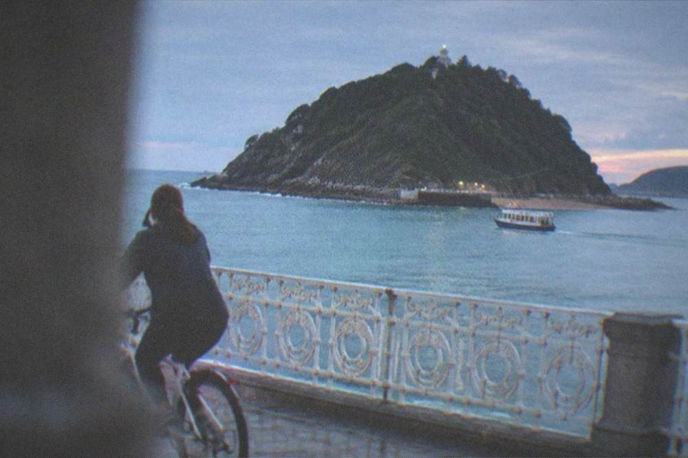 A cyclist riding along the La Concha promenade with the bay and Santa Clara island behind